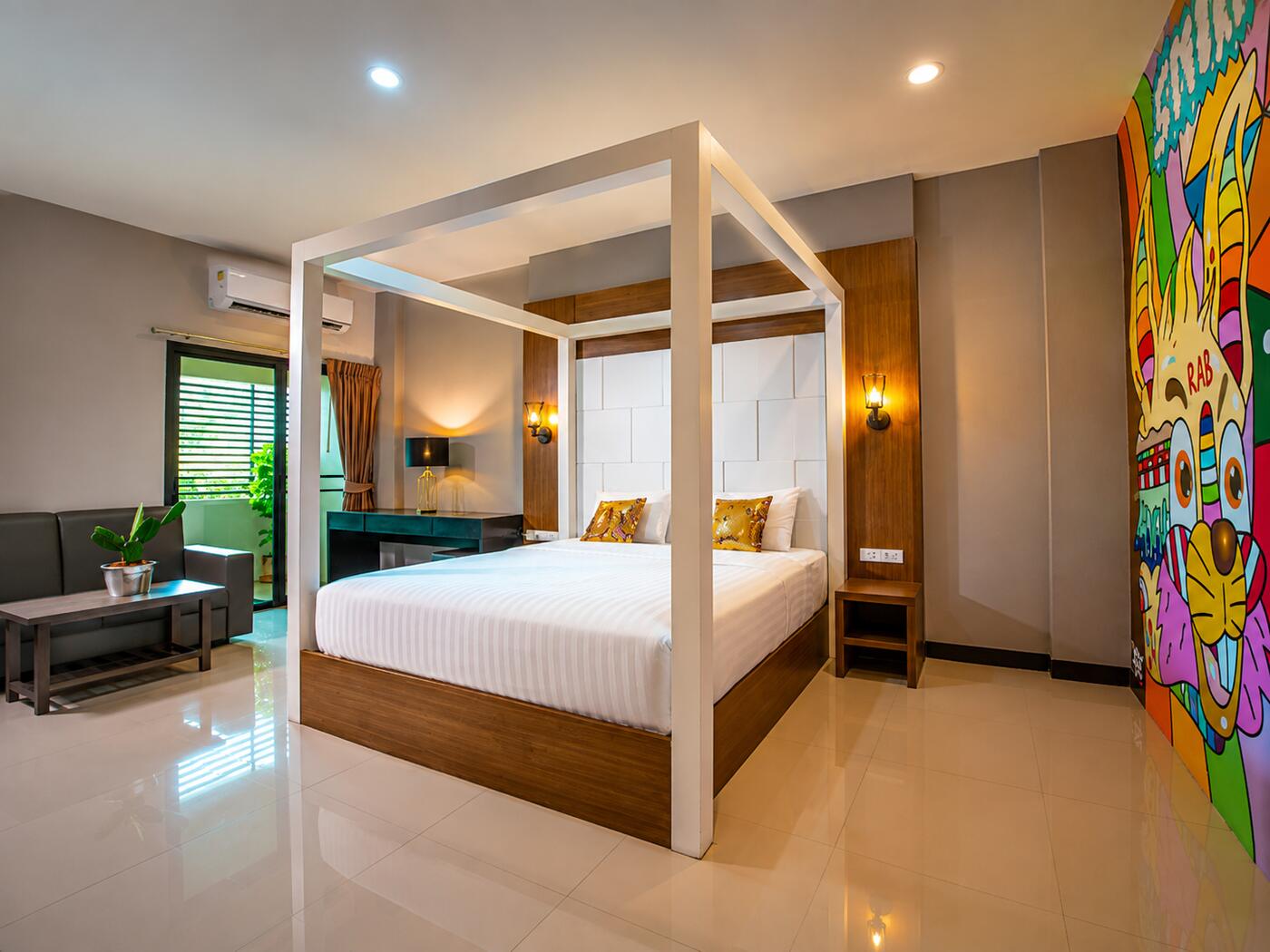 ห้อง Deluxe Suite เตียงจัดเรียบร้อยพร้อมมุมนั่งเล่นแยกจากพื้นที่นอน